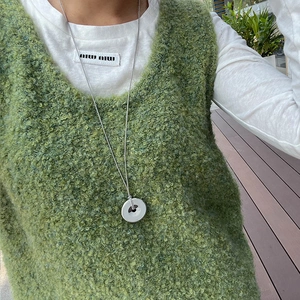 Detail of silver long chain necklace featuring a smooth white round donut pendant on model