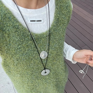 Close-up of minimalist silver organic pendant and ring necklace on model outfit