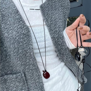 Detail of a minimalist long apple pendant necklace with dark red high-gloss finish