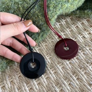 Macro shot of black and burgundy glossy circle charms with matching long cords