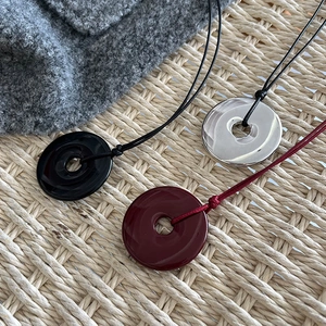 Detailed close-up of minimalist circular resin and metal pendants in black red and silver