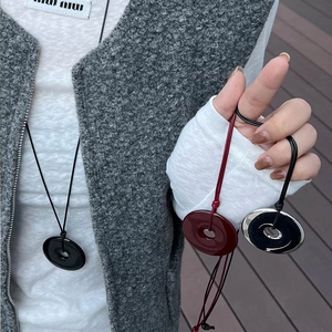Detailed close-up of three minimalist donut pendants on simple cords against wool fabric