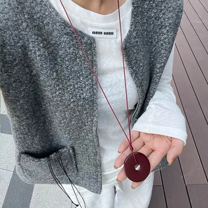 Detail of minimalist long necklace featuring a solid dark red round agate stone pendant