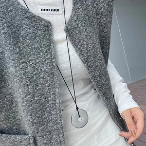 Detail of grey sherpa vest with metal zipper and long minimalist circle pendant necklace