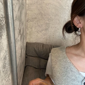 Minimalist silver heart drop earrings with polished finish worn by a model in lifestyle shot