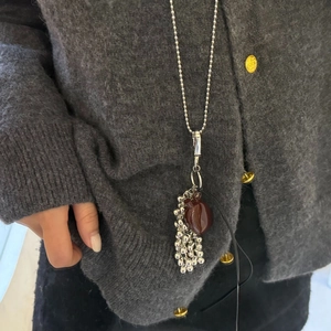 Detail of silver ball chain necklace featuring a dark red heart pendant and bead tassels