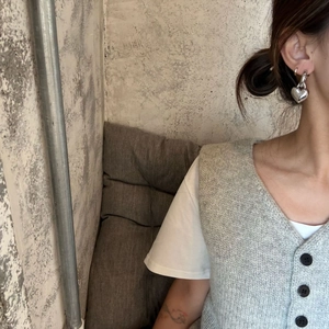 Close-up of minimalist silver double heart earrings worn by a model in industrial setting