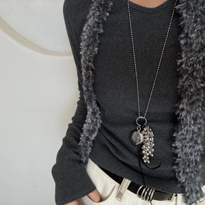 Detail of silver beaded cluster and heart pendant on long chain worn with sweater