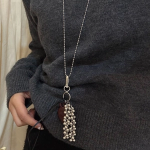 Close-up of a silver beaded long sweater chain featuring a dark red heart pendant