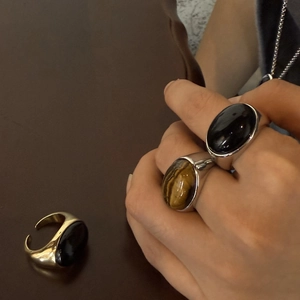 Vista detallada de anillos ovalados de ojo de tigre y obsidiana con banda ajustable