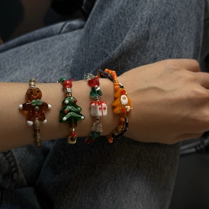 Detailed view of Christmas gingerbread man and Santa glass bead bracelet set worn on wrist