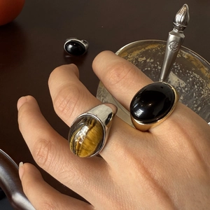 Detalle macro de anillos ovales de ojo de tigre y ónix con monturas vintage