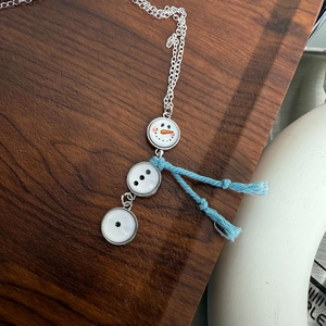 Macro detail van sneeuwpop hanger ketting met blauwe sjaal en zilveren schakels
