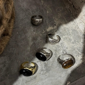 Colección retro de anillos ovalados de ojo de tigre y obsidiana en superficie de piedra