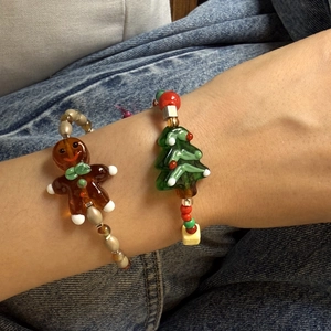 Close-up of festive Christmas bracelets with gingerbread man and tree charms on a model