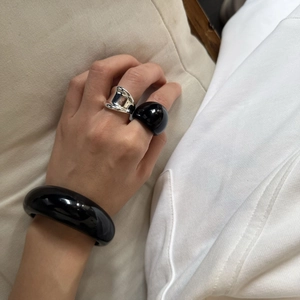 Primo piano del bracciale minimalista in resina nera e set di anelli d'argento sulla mano