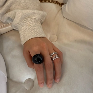 Dettaglio di un grande anello in resina nera abbinato a anelli impilabili in argento