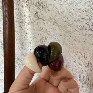 Dettaglio di anelli in resina spessa in avorio nero oliva e rosso scuro sulla mano