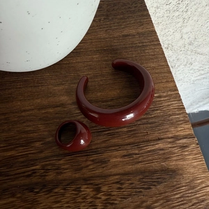 Dettaglio del set di gioielli in resina rosso scuro con bracciale lucido e anello spesso