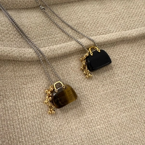 Detail of mini handbag pendants with tiger eye stone and black beads on silver chain