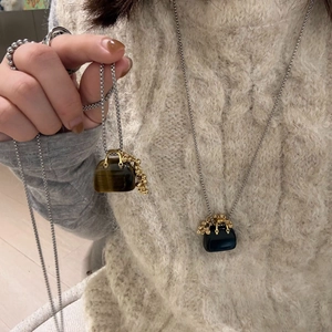 Detail of tiger eye and obsidian mini bag pendants on a knitted sweater background