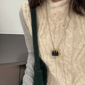 Macro shot of a vintage doctor bag pendant necklace with tiger eye on a beige sweater