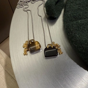 Detail shot of mini handbag pendant with tiger eye and black onyx on a silver chain