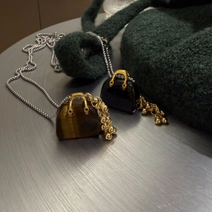 Macro shot of tiger eye stone bag pendant on a textured dark green fabric background