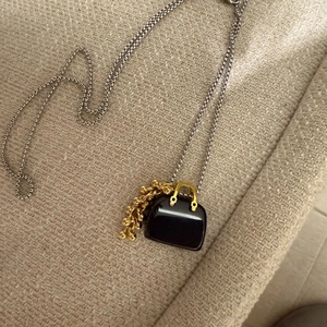 Detailed macro view of the black handbag pendant featuring golden accents and chain