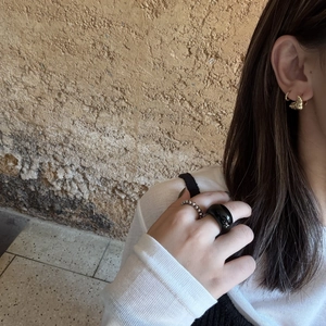 Detail eines schwarzen polierten breiten Rings und Silberperlenrings an einer Frauenhand