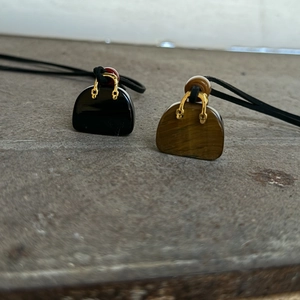 Minimalist mini handbag pendants in black and tiger eye stone on dark stone background