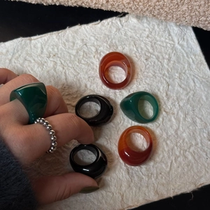 Nahaufnahme von Retro-Breitharz-Achatringen in Dunkelgrün, Schwarz und Orange-Finish