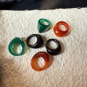 Sechser-Set breite Achat-Ringe in Grün, Schwarz und Orange auf strukturiertem Hintergrund
