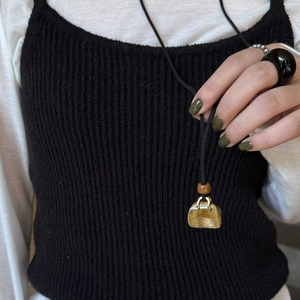 Tiger eye handbag pendant on black cord necklace styled with knit vest and white shirt