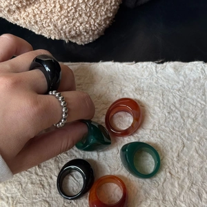 Nahaufnahme von breiten Retro-Resinringen in Schwarz, Grün und Amber mit Silberperlen