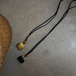 Macro detail of handbag-shaped tiger eye and onyx stone pendants on long black cords