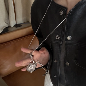 Silver woven basket pendant necklace with metal bead chain on black leather jacket