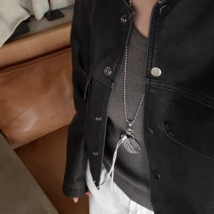 Close-up of heart-shaped handbag pendant necklace styled with black leather jacket