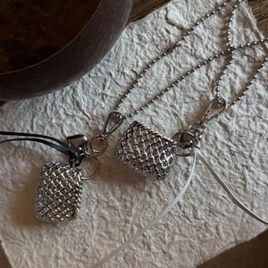 Macro view of silver woven cube pendants with leather strap and metal beaded chain