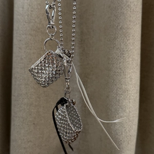 Macro detail of miniature silver woven bag pendants and sleek ball chain texture