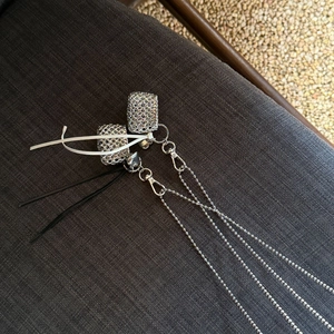 Macro shot of silver woven metal bag pendant and delicate ball chain link detail