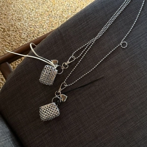 Detailed shot of silver woven bag pendant with heart charm on beaded sweater chain