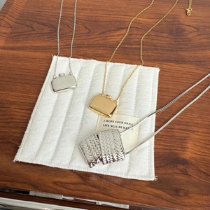 Nahaufnahme von Parfümflaschen-Anhängern in Gold und Silber mit gewebten Metalldetails