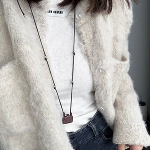 Lange Halskette mit braunem Koffer-Anhänger und schwarzer Schnur für einen eleganten Look