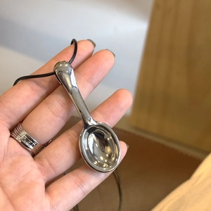 Detalle del collar con colgante de cuchara con acabado de espejo pulido en un cordón negro