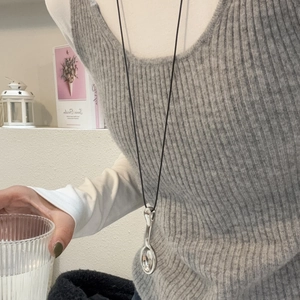 Primer plano de collar con colgante de cuchara plateada y cordón negro en una modelo