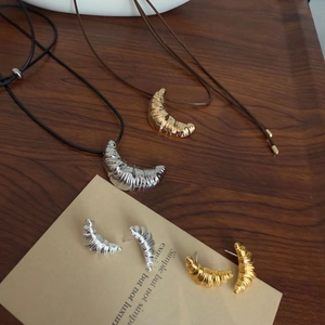 Detail of croissant-shaped gold and silver jewelry sets on a dark wooden tray