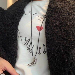 Silver croissant pendant on a black leather cord worn over a white heart-patterned T-shirt