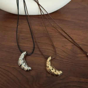Detailed view of gold and silver croissant pendants with textured pleats on cord necklace