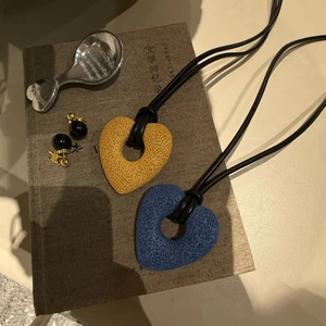 Artistic hollow heart pendant with volcanic stone texture on long black cord necklace